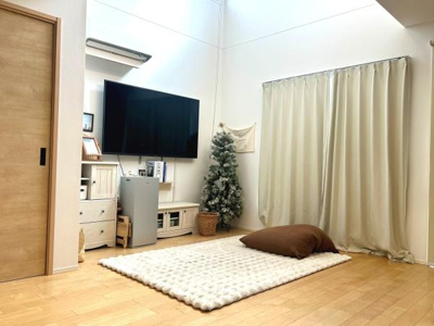 開放感のあるリビングは大きな窓からたっぷり光が入ります。壁付けテレビや収納スペースが整然と配置されています。すっきりとした内装と温かみのあるフローリングが印象的です。