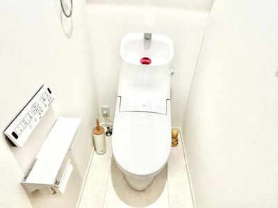 シンプルで清潔感のあるトイレ空間です。壁リモコンが使いやすくペーパーホルダーも備え付けられています。床まで明るい色合いで圧迫感を感じにくい設計です。手洗い付きで衛生面にも配慮されています。