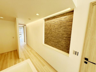 石調のアクセントウォールが印象的な玄関スペースです。明るいフローリングとの組み合わせで空間が広く感じられます。照明が柔らかく清潔感のある仕上がりです。