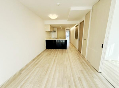 広々とした空間が広がるリビングです。明るい床材が空間全体をやわらかく見せ開放感を演出しています。窓から差し込む光がリビング全体を明るくしています。仕切りを活用して柔軟な使い方が可能です。