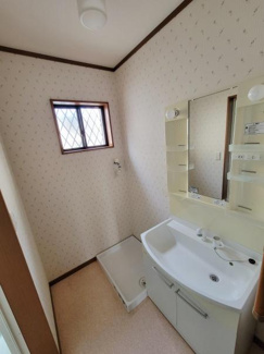 明るい窓があり自然光が差し込む洗面所です。収納棚付きの大きな鏡が実用的です。シンプルなデザインでお手入れもしやすい空間になります。洗面台横に洗濯機置き場が設けられています。