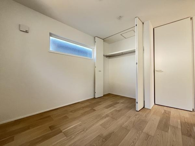 明るい色合いのフローリングが特徴ですっきりとした印象の洋室です。クローゼットが備え付けられているので収納も充実しています。横長の窓が採光を確保し室内を明るく保ちます。