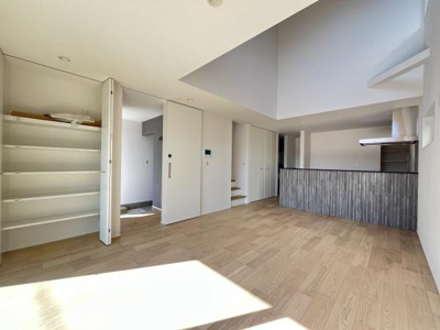 リビングには大きな窓から光が差し込み明るい空間が広がります。開放感のある高い天井が特徴です。収納スペースも充実しておりすっきりとした印象です。キッチンとのつながりもスムーズな設計です。