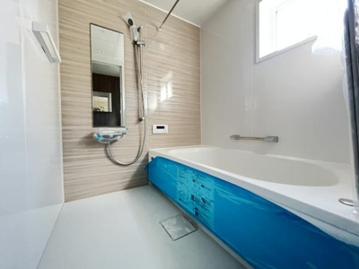 明るい印象のバスルームで浴槽は広々とした設計です。壁面にはグレーのパネルが使用され清潔感があります。窓から自然光が差し込みすっきりとした空間を演出しています。