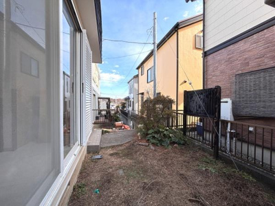 周囲にフェンスが設置されており安心感があります。室外機や外部設備もわかりやすい配置です。日差しがしっかり差し込む明るい雰囲気の庭先です。住まいの外観が整っており隣家との距離感も確保されています。