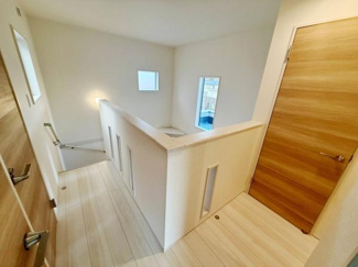 明るい光が差し込む廊下で開放感のある空間です。ナチュラルな木目の扉が落ち着いた雰囲気を演出しています。白を基調とした内装が清潔感を感じさせます。階段やドアへのアクセスがスムーズな配置もポイントです。