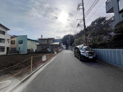 前面道路は道幅がしっかりと確保されており車の出し入れもスムーズです。周囲は落ち着いた住宅街で静かな環境が広がっています。電柱や緑もあり自然を感じられる景観です。