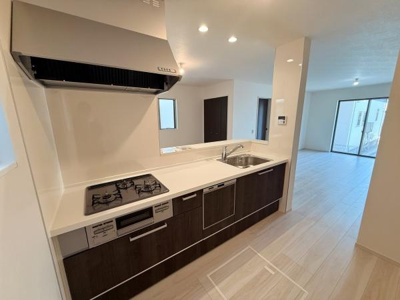 シンプルで明るいキッチン空間が広がっています。収納スペースも充実しており使い勝手が良い設計です。シンクやコンロ周辺もすっきりとまとまっています。カウンター越しに開放的なリビングが見渡せる配置です。