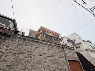 堅牢な石垣が目を引く外観です。高台に位置した住まいで開放感が感じられます。バルコニーも利用しやすい設計です。周囲には住宅が整然と建ち並んでいます。