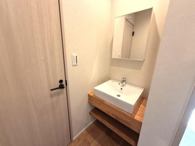 洗面台はシンプルなデザインで清潔感のある印象です。ナチュラルな木目調のカウンターが空間に温かみをプラスしています。明るい照明が毎日の身支度をサポートします。