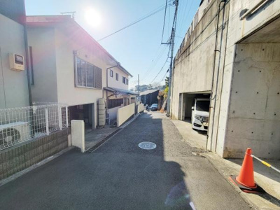 前面道路は舗装されており車の出入りもしやすい印象です。周辺は閑静な住宅地で整然とした街並みが広がっています。道路幅も十分にあり日当たりの良い現地写真です。建物やブロック塀もきれいに整備されています。