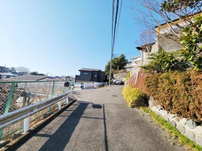 前面道路は幅もあり車の通行もしやすい環境です。舗装状態も良好で安心してご利用いただけます。周辺は住宅が並んでおり落ち着いた雰囲気が漂います。現地は日差しが差し込み開放的な空間が広がっています。