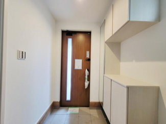 明るく開放感のある玄関スペースです。玄関収納が充実しておりすっきりとした印象を与えます。ホワイトを基調とした内装が清潔感を演出しています。木目調のドアがデザインのポイントになっています。