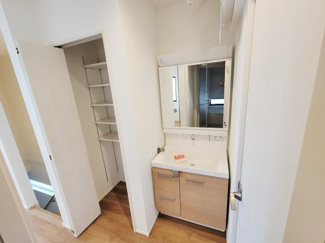 収納棚が備え付けられている洗面台があり使いやすいスペースが確保されています。ナチュラルな色合いの木目調が空間に調和しています。広さもあり日々の身支度が快適に行えそうです。