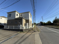 前面道路が広く開放感のある現地写真です。道路沿いに電柱や配線が整然と配置されています。歩道も設けられており道路状況がわかりやすいです。建物外観や周辺の雰囲気も確認できます。