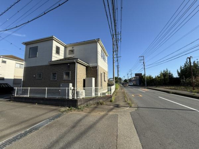 前面道路が広く開放感のある現地写真です。道路沿いに電柱や配線が整然と配置されています。歩道も設けられており道路状況がわかりやすいです。建物外観や周辺の雰囲気も確認できます。