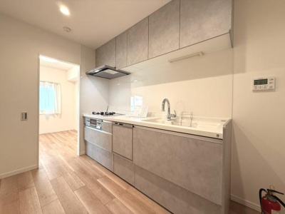 収納が充実したシンプルなデザインのキッチンです。開放感のある空間で使いやすさを重視しています。清潔感のあるカラーリングが印象的です。広めの作業スペースも確保されています。