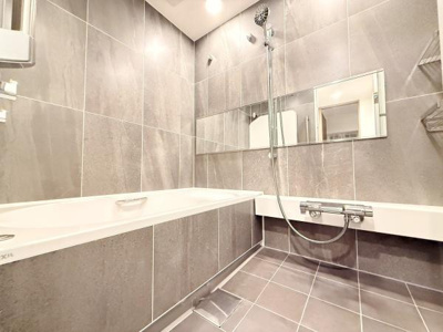 落ち着いた色合いのタイルが上質な雰囲気を演出します。広々とした浴槽はリラックスできる空間です。洗い場と浴槽が分かれ機能性に配慮されたバスルームです。浴室全体が明るく清潔感があります。