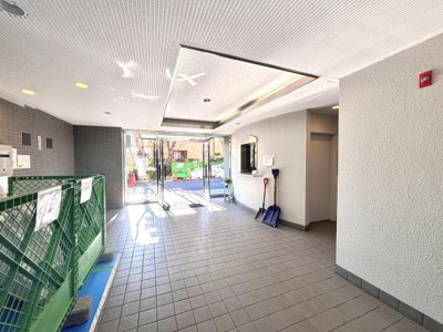 明るいエントランスはガラス扉で開放感があります。タイル張りの床が清潔感を感じさせます。入口付近には案内板や道具の収納スペースも整っています。通路も広々としており日当たりが良好な印象です。