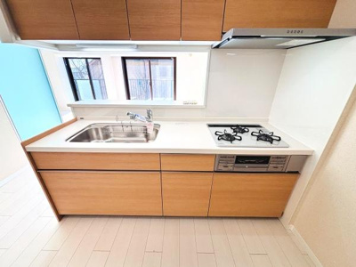 明るい色合いのキッチンが清潔感を演出しています。広々とした作業スペースを確保しています。3口コンロが設置されており使い勝手が良い仕様です。大きな窓があり十分な採光が確保されています。