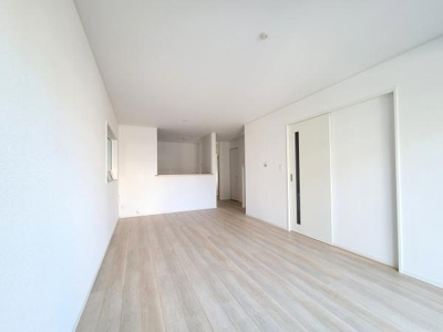 白を基調とした内装が明るい印象を与えます。広々としたリビングスペースで空間にゆとりがあります。大きな引き戸がすっきりとした印象を強調しています。キッチンとのつながりも良好です。