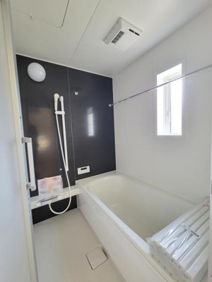 シンプルな配色がスタイリッシュな印象のバスルームです。浴槽と壁のコントラストが空間を引き締めています。窓があり明るい光が差し込みます。浴室乾燥機が設置されているのも便利です。