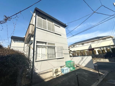 白を基調としたシンプルな外観が特徴の住宅です。角地に位置しており開放感があります。窓が大きく日差しがしっかり入る設計です。外にはエアコン室外機やゴミ置き場も設置されています。