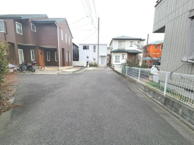 幅広い前面道路が特徴的な現地写真です。周辺は新しい住宅が並び落ち着いた雰囲気が伝わります。周囲の街並みや建物もよく整えられておりすっきりとした印象です。敷地前のスペースも広めに確保されています。
