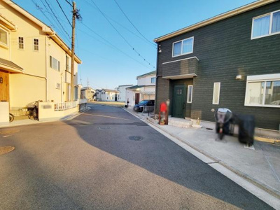 前面道路が広く車の出し入れがしやすい現地写真です。周囲には住宅が整然と並び開放感のある街並みが特徴的です。舗装された道路で歩行や自転車の移動も快適に行えます。日当たりが感じられる環境となっています。