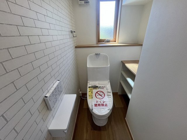 窓付きで明るく換気しやすいトイレです。アクセントクロスやカウンター収納を採用し、清潔感と機能性を兼ね備えた空間に仕上がっています。