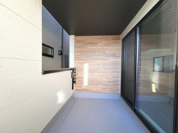 すっきりとした直線的なデザインのバルコニーです。スライドガラスドアが採用されており開閉もスムーズです。壁面には落ち着いた色調の外壁材が使われています。奥までしっかりとスペースが確保されています。