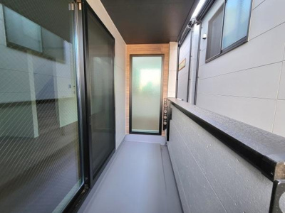 すっきりとした直線的なデザインのバルコニーです。スライドガラスドアが採用されており開閉もスムーズです。壁面には落ち着いた色調の外壁材が使われています。奥までしっかりとスペースが確保されています。