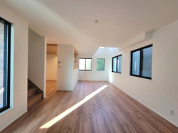 大きな窓から自然光がたっぷり入るリビングです。落ち着いた色合いのフローリングが空間を引き締めています。天井が高く開放感があります。シンプルなデザインがインテリアを引き立てます。