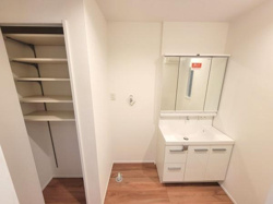 シンプルで清潔感のある洗面台が設置されています。収納スペースも豊富に確保されています。鏡も大きめで使いやすい設計です。必要な機能がしっかり備わっています。空間がすっきりとまとまっています。