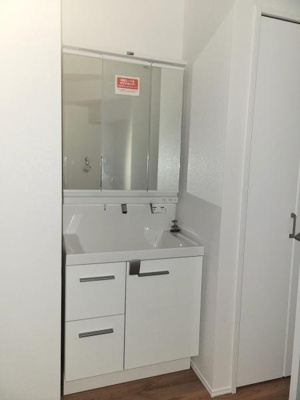 シンプルで清潔感のある洗面台が設置されています。収納スペースも豊富に確保されています。鏡も大きめで使いやすい設計です。必要な機能がしっかり備わっています。空間がすっきりとまとまっています。