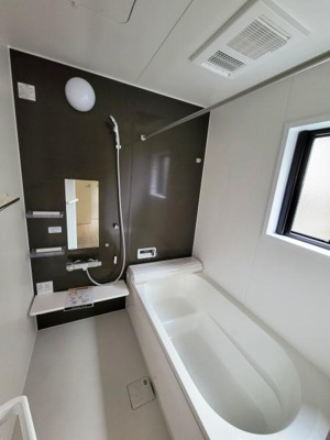 シンプルで洗練されたデザインのバスルームです。大きな窓があり自然光をしっかりと取り入れます。壁面には便利な収納棚とミラーが設置されています。シャワーと浴槽が独立しており使い勝手を重視した設計です。