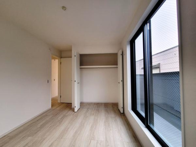 クローゼットが備わっており整理整頓がしやすい空間です。室内はシンプルでまとまりがあり明るい雰囲気が広がります。床材の色合いが落ち着いた印象を与えています。大きな窓からはしっかりと光が入ります。