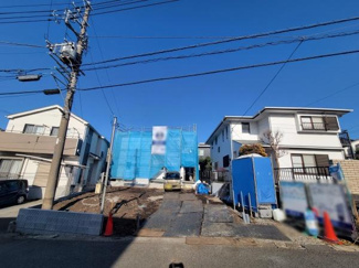 建築中の現場の様子がよく分かる写真です。前面道路から敷地へのアクセスも確保されています。隣接する住宅との距離感も一目で分かります。電柱や電線の配置も確認することができます。