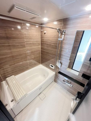 ゆったりとしたバスタブが特徴的な洗面所です。木目調パネルが空間に落ち着きを与えます。大きな鏡が設置されており明るく広々とした印象です。浴室乾燥機の設置も確認できます。