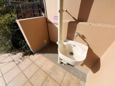 屋外に設置された便利な水栓で手軽に水の利用ができます。周囲に壁がありプライバシーも確保されています。メンテナンスもしやすいデザインです。陽当たりの良い場所に設置されています。