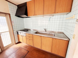 木目調の収納が特徴のキッチンです。壁一面のタイルが清潔感を演出します。