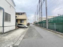 前面道路が広く車の出し入れがしやすい現地写真です。周囲にはフェンスや住居が隣接しすっきりとした街並みが特徴です。道幅も確保されており落ち着いた雰囲気が感じられます。