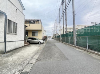 前面道路が広く車の出し入れがしやすい現地写真です。周囲にはフェンスや住居が隣接しすっきりとした街並みが特徴です。道幅も確保されており落ち着いた雰囲気が感じられます。