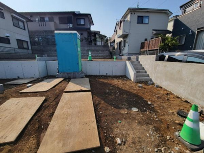 基礎工事が進行中の土地写真です。周囲は住宅街で落ち着いた環境が広がっています。階段付きのアプローチがありアクセスが便利です。敷地は整った形状で今後の施工がしやすそうです。