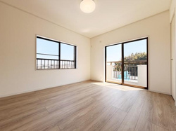 2面の大きな窓からたっぷりと自然光が入る洋室です。木目調の床が落ち着いた印象を与えます。広々とした空間が特徴的です。バルコニーへのアクセスも便利です。清潔感のある内装が魅力です。