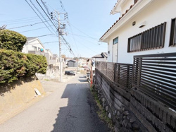 現地写真は落ち着いた住宅街の雰囲気が伝わる前面道路の様子です。周囲の建物や道路の幅が視認でき日当たりの良さも感じられます。道路沿いの植栽やフェンスも手入れされており整然とした印象です。