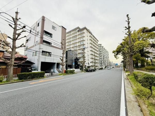 前面道路は見通しが良く広々とした印象です。周辺には高層マンションやビルが立ち並び開放感があります。道路沿いには歩道も整備されています。緑も感じられる環境です。都市的な景観が特徴です。