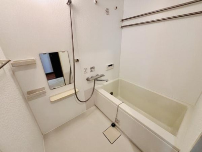 明るい色合いのバスルームが清潔感を感じさせます。浴槽と洗い場がしっかり分かれており鏡や小物置きも設置されています。シャワーホースや手すりも備わっていて日々の使いやすさに配慮された空間です。