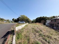 現地の様子がよくわかる写真です。前面道路は広く車両の出入りもしやすそうです。周囲には緑が多く開放的な雰囲気が感じられます。住宅も隣接しており生活のイメージがしやすい立地です。