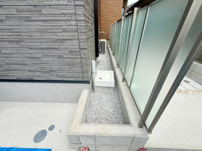 建物とフェンスの間に設けられたスペースに外水栓が設置され便利に使える設計です。グレーの外壁材やフェンスが調和し落ち着いた雰囲気を演出しています。